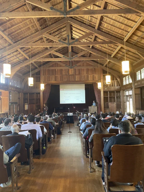Conference attendees seated beneath the timber beams of the meeting hall.