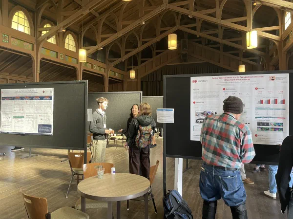 Conference participants discuss research beside scientific posters.